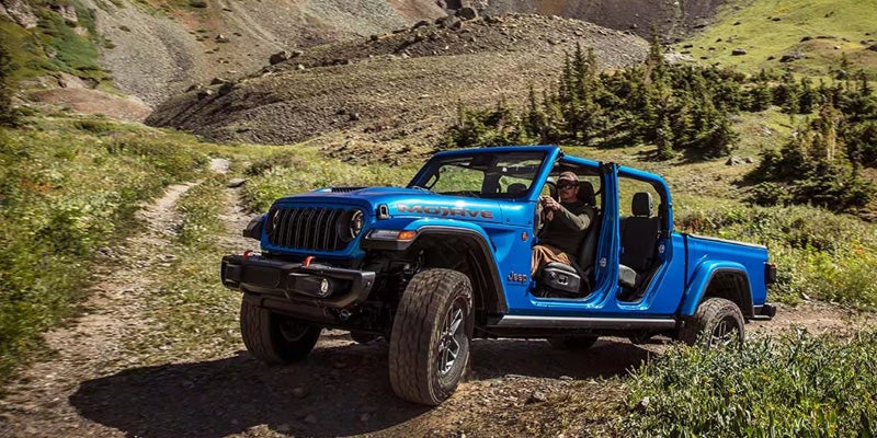 Jeep Gladiator pickup truck driving on mountain trail terrain
